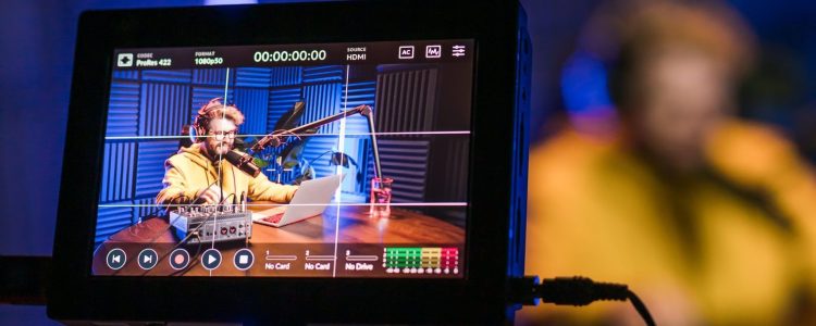 Cheerful young man recording podcast in studio. Confident man with headphones and microphone recording a podcast. Happy guy talking on web radio